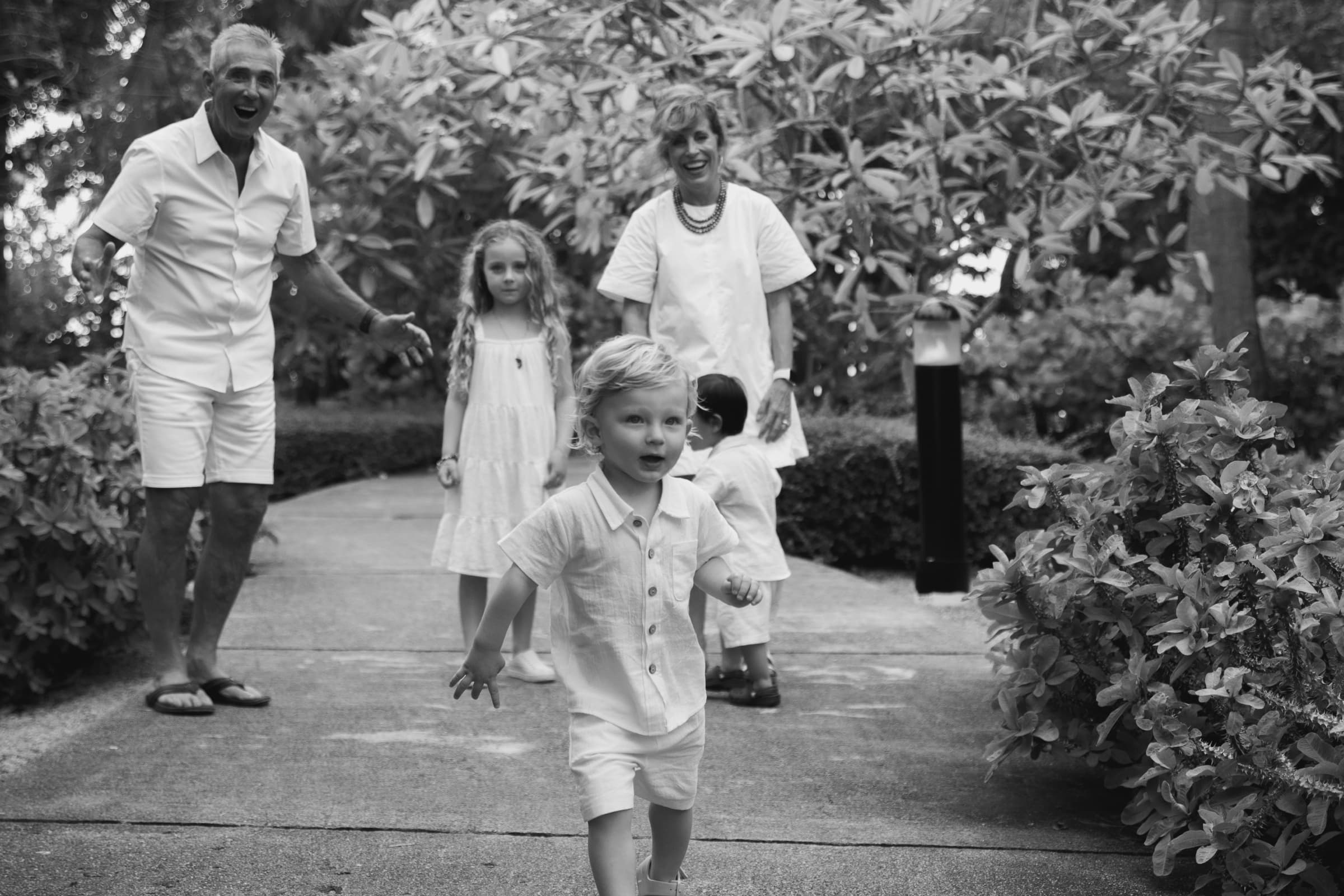 Grandparents and grandchildren laughing together on a garden path