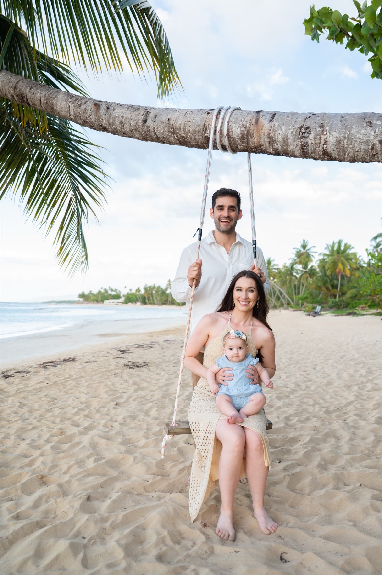 A family of three on a palm-tree swing at the beach, Dominican Republic