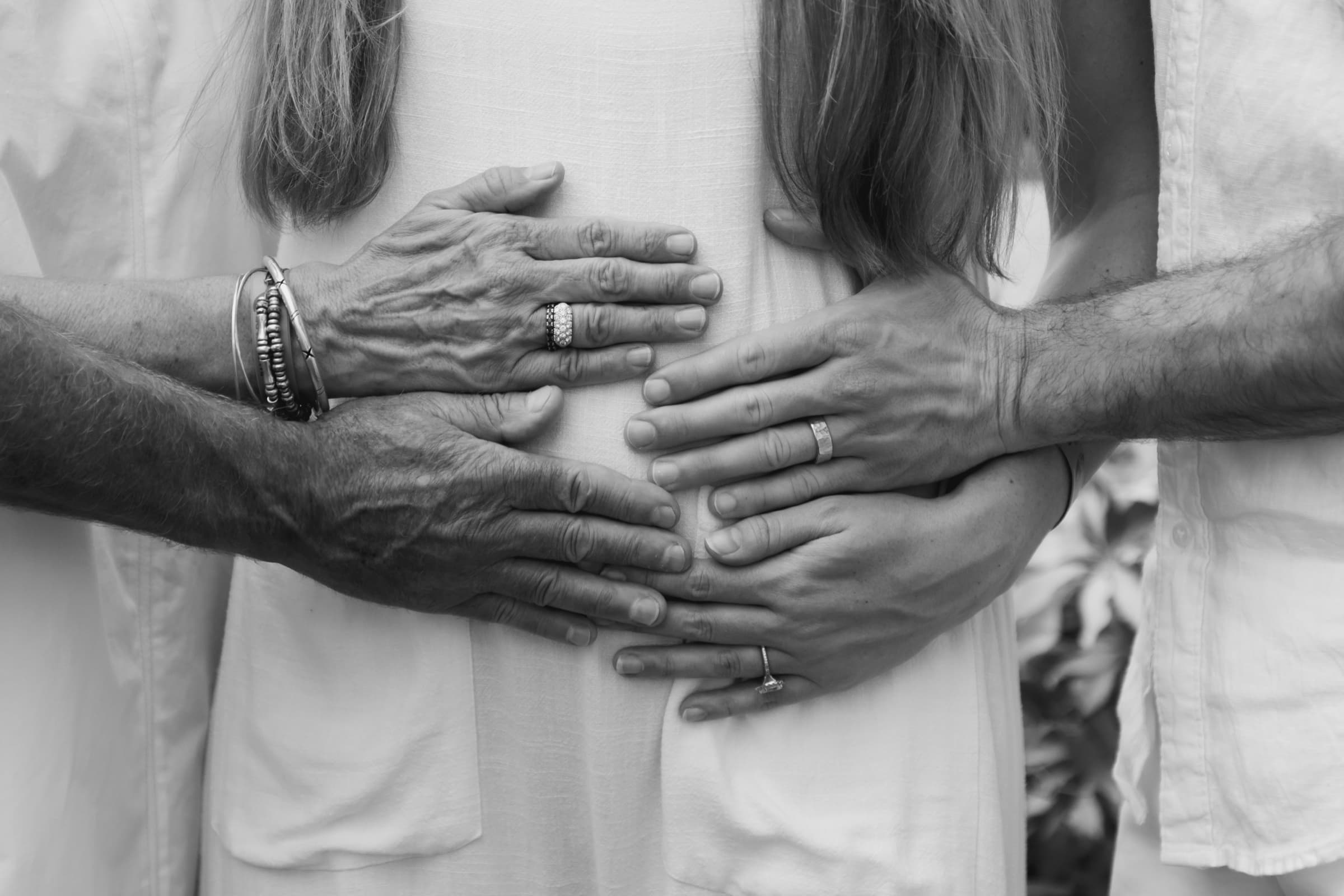 Three generations of hands resting together, black and white
