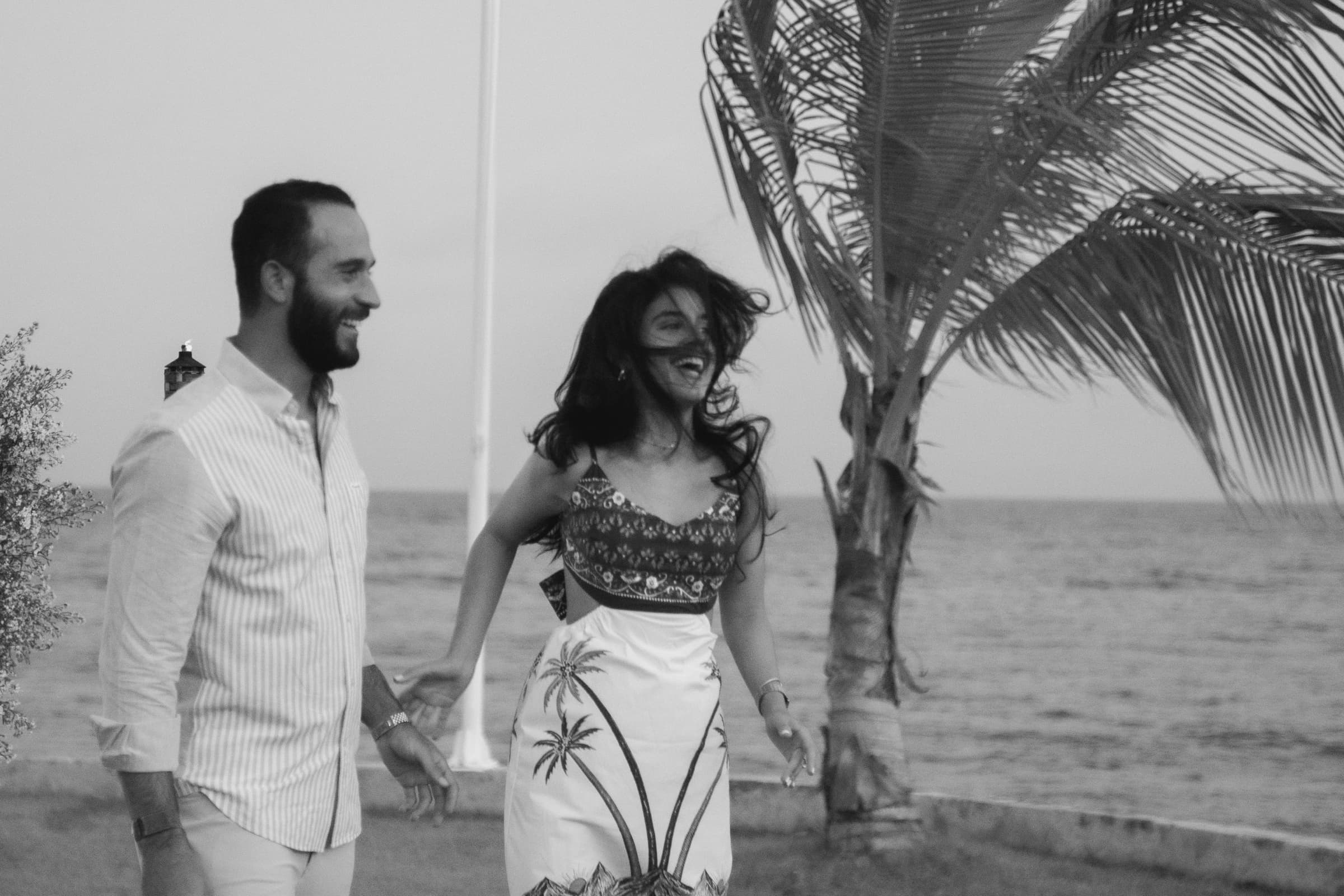Victor & Carola walking and laughing by the water, black and white