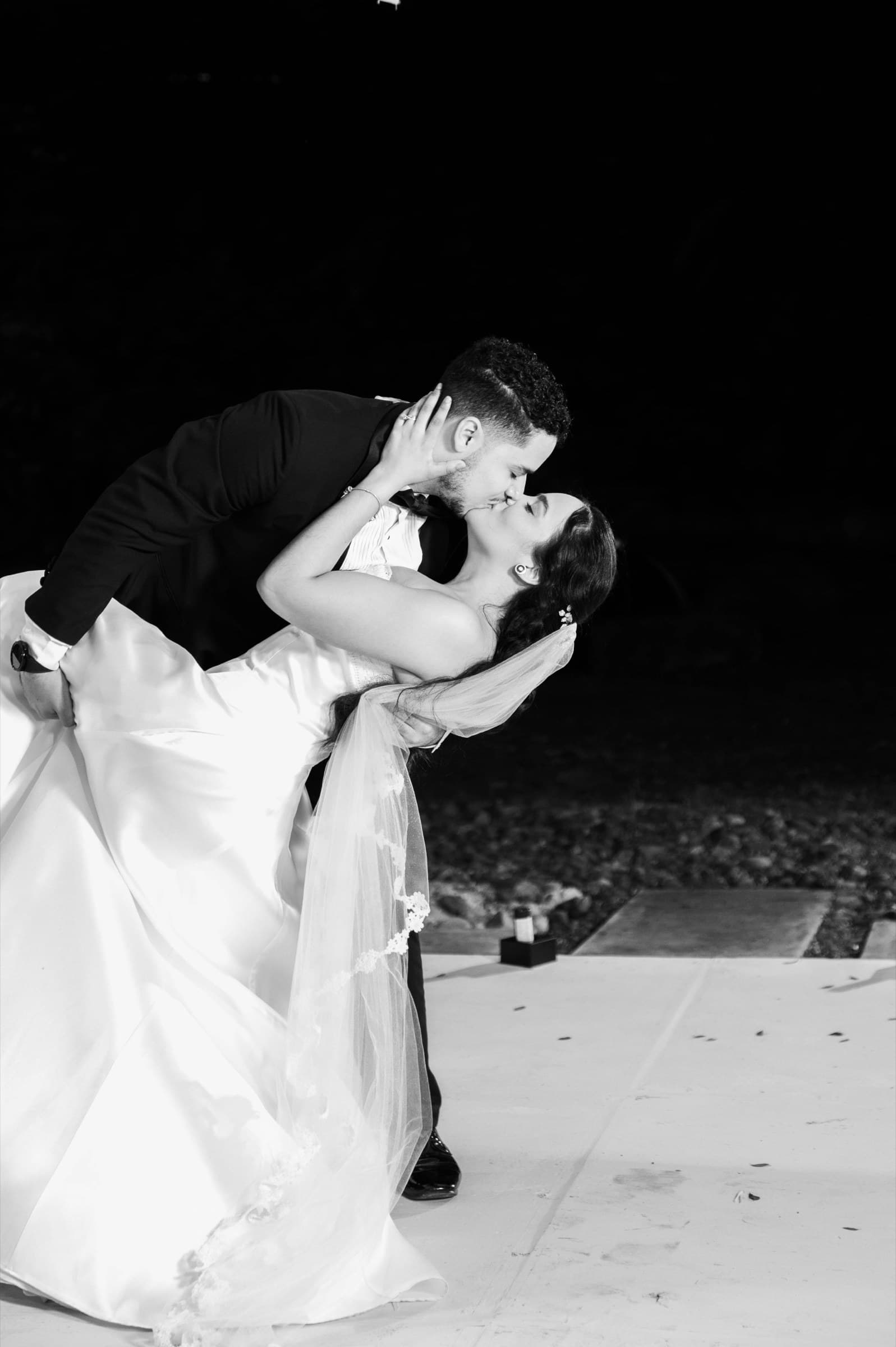 Zeta & Daniel dipped in a kiss on the dance floor at night, black and white
