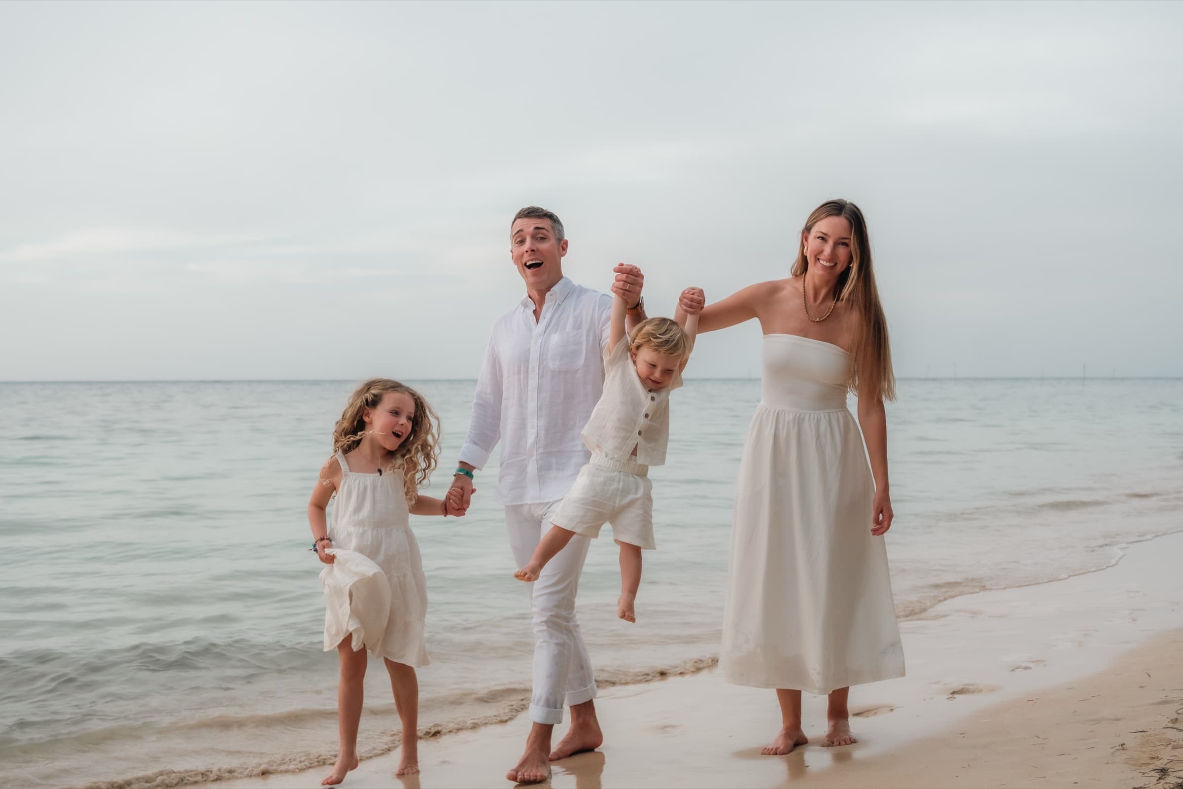 A family of four walking along the shoreline, Dominican Republic